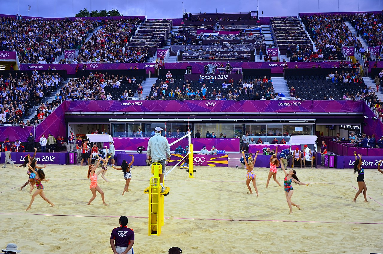 Dancers entertain crowds in a temporary beach volleyball stadium constructed of temporary steel staging and seating.